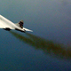 A photo showing streams of black smoke coming from the engines of a Concorde plane.